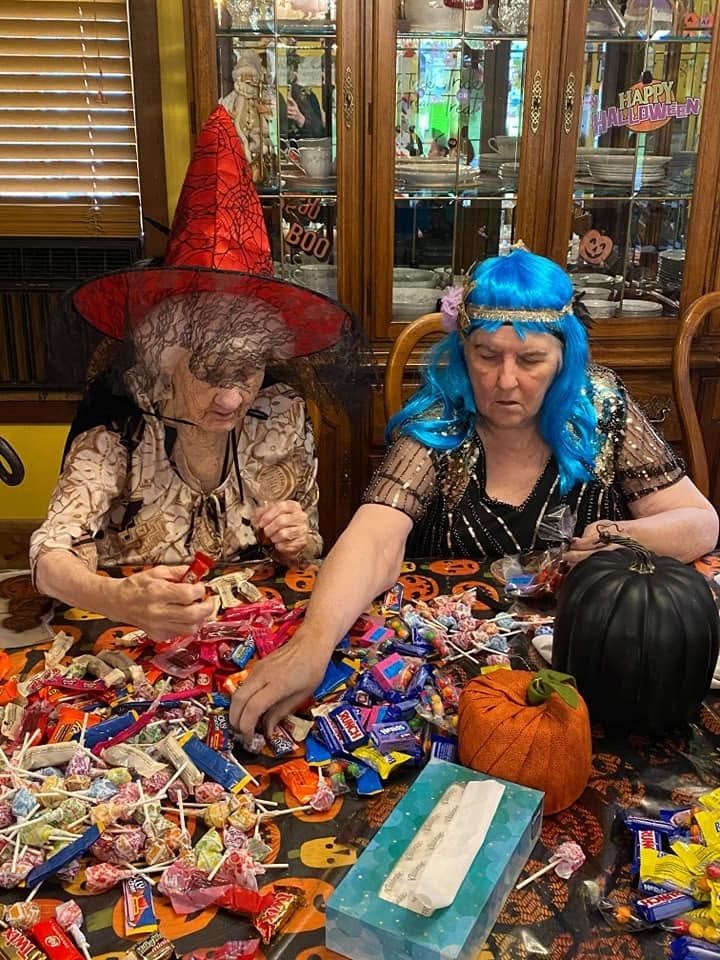 A resident and Traci in costume sorting through a mountain of Halloween candy at the table