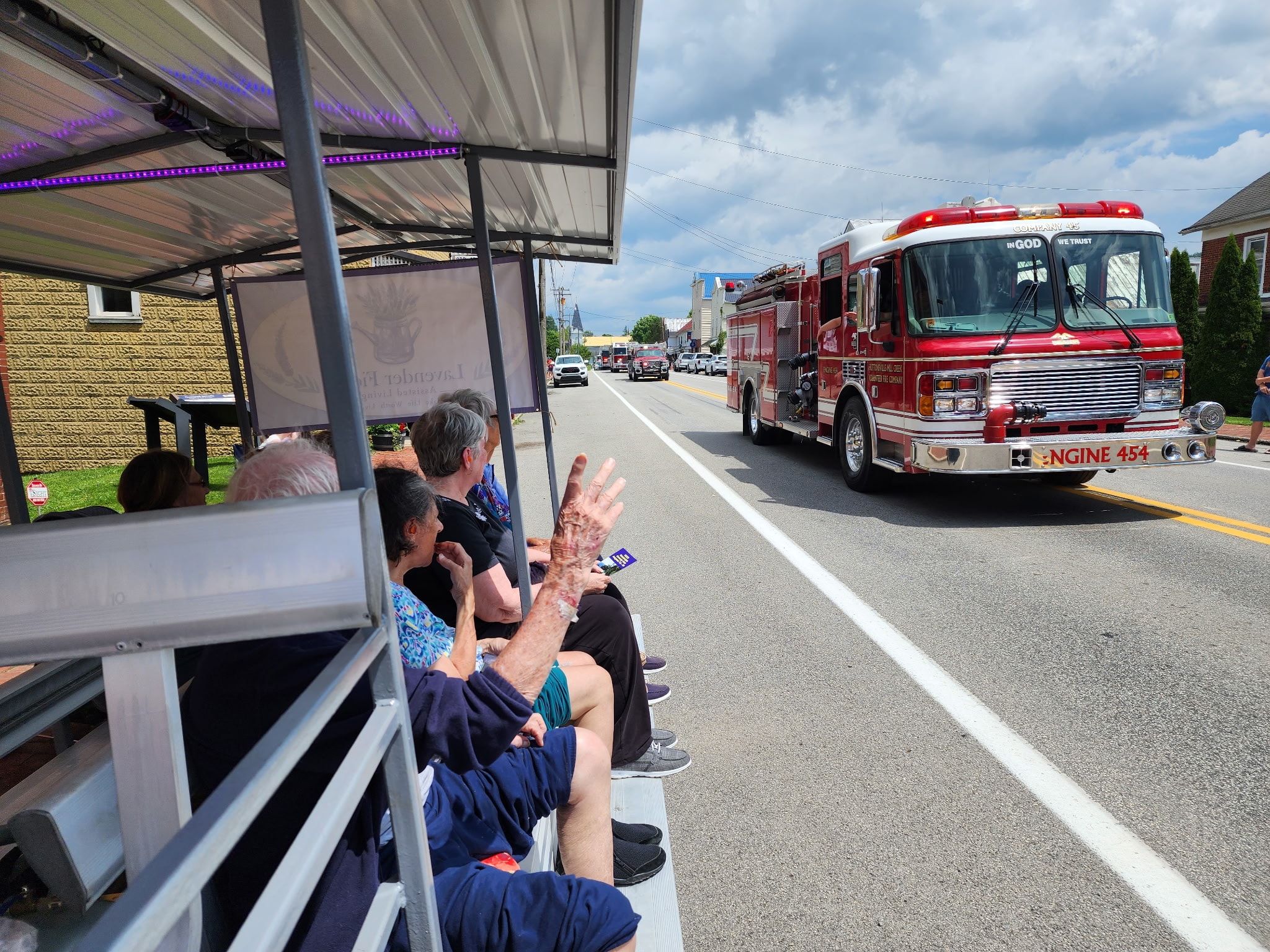 Lavender Fields residents watching a fire truck pass during a Beverly parade from the community tram