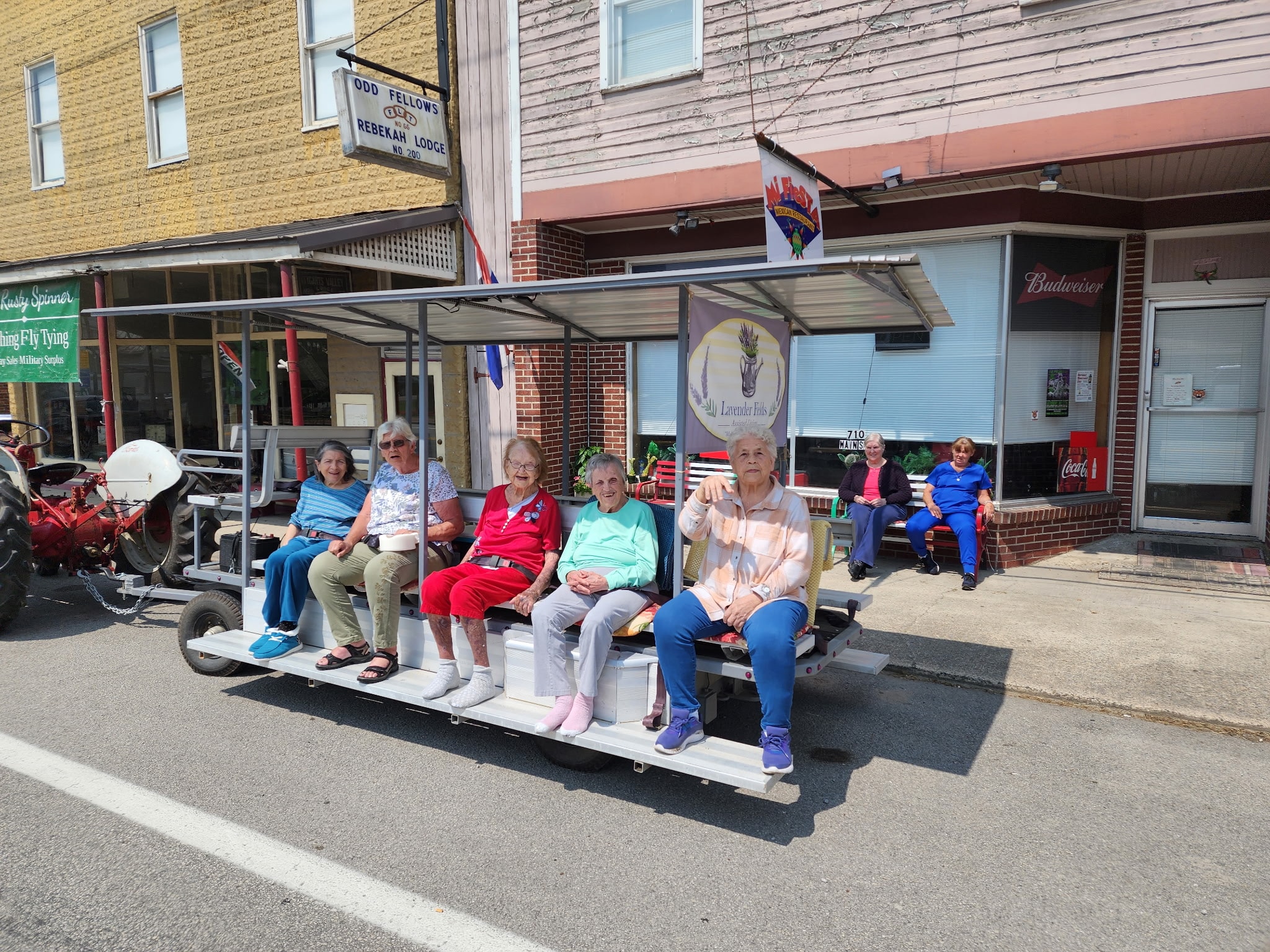 Lavender Fields residents seated on the community tram on Main Street in Beverly with the Lavender Fields banner
