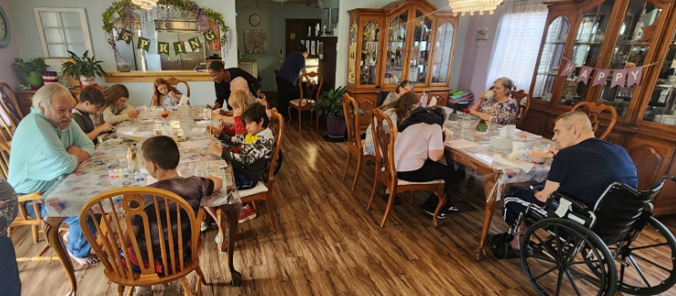 Beverly Grade School students and Lavender Fields residents seated together at the dining room tables doing a spring craft project