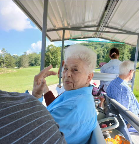 A resident on a golf cart outing, turning to smile at the camera with green fields behind her
