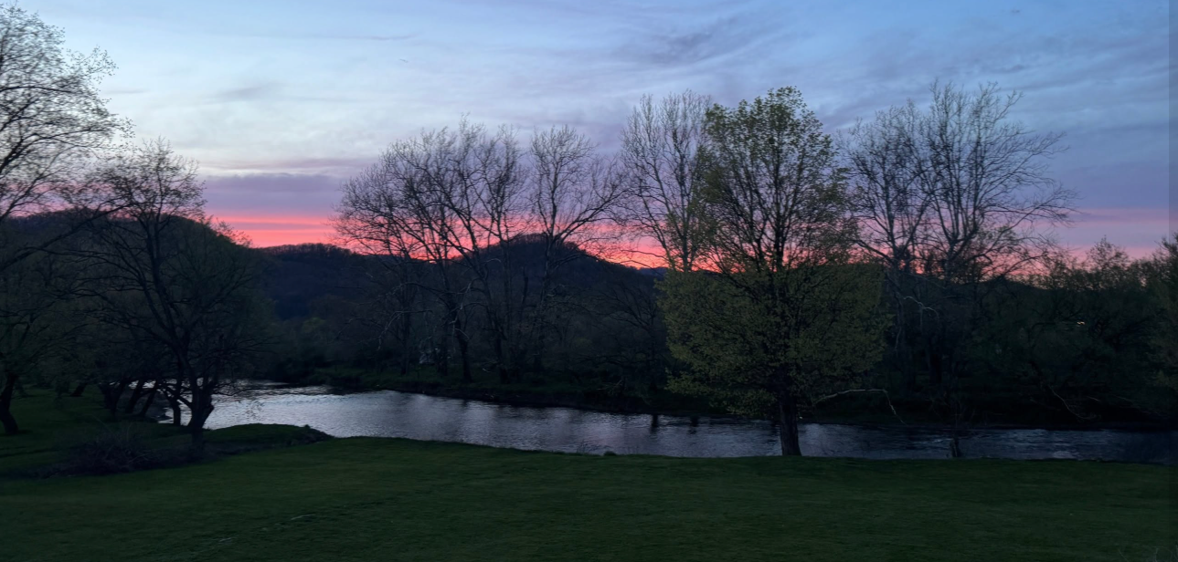 Sunset over the Tygart Valley River behind Lavender Fields Assisted Living in Beverly, West Virginia, with hills and trees in silhouette.