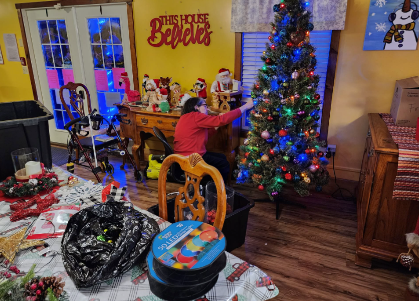 A staff member decorating the Christmas tree in the Lavender Fields living room